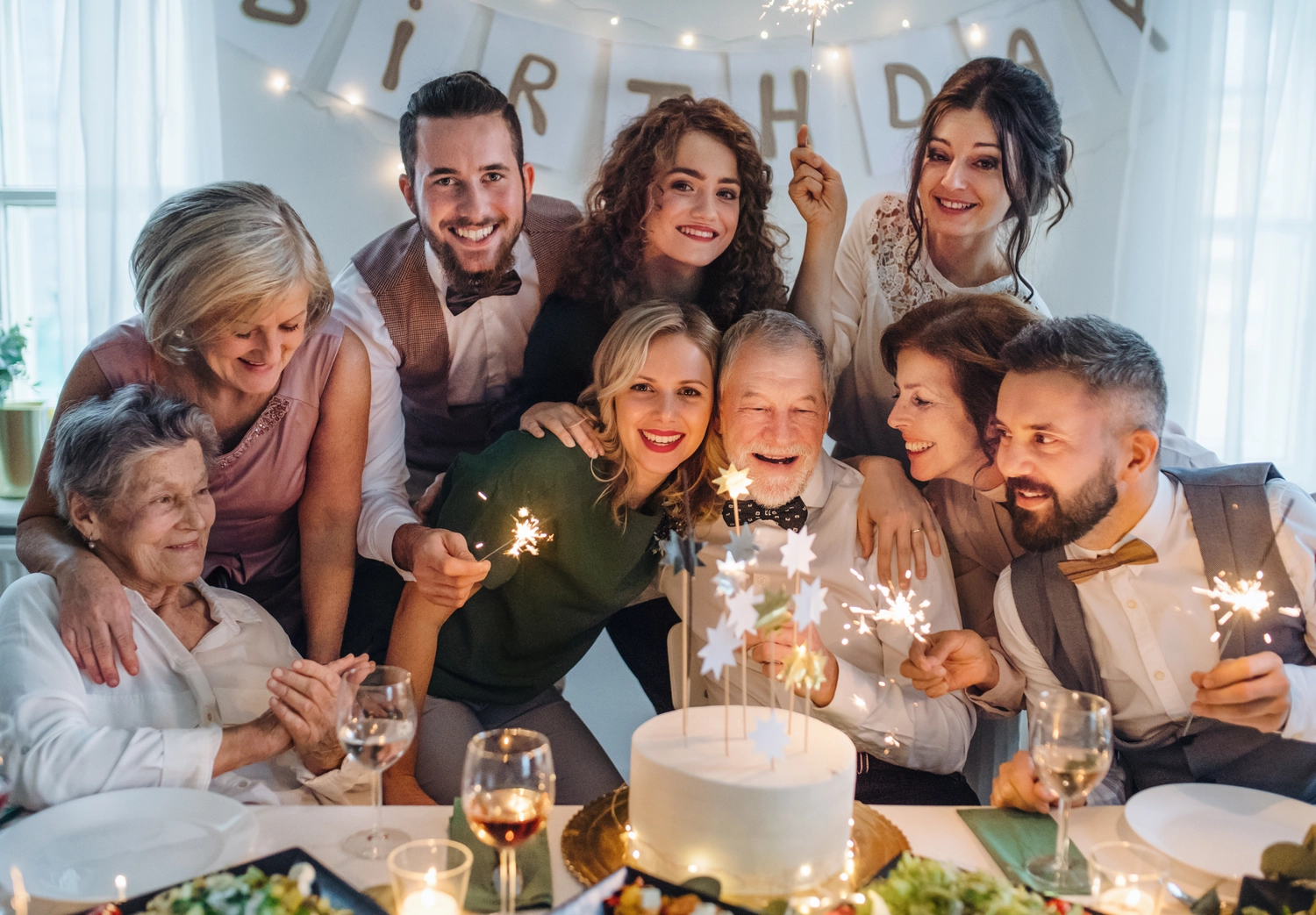 Ein älterer Mann feiert mit seiner Mehrgenerationenfamilie seinen Geburtstag auf einer Indoor-Party.